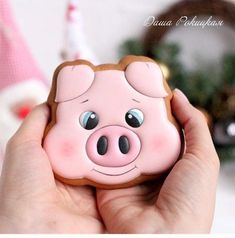 a hand holding a cookie shaped like a pig