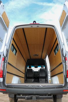 the back end of a white van with open doors and wood paneling on it