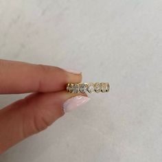 a woman's hand holding a gold ring with five diamonds on the middle of it