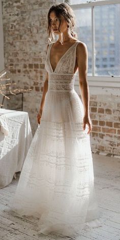 a woman standing in front of a window wearing a wedding dress