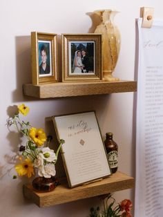 two wooden shelves with pictures and flowers on them next to an open book, framed photos