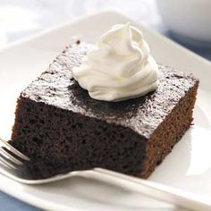 a piece of chocolate cake with whipped cream on top is sitting on a white plate