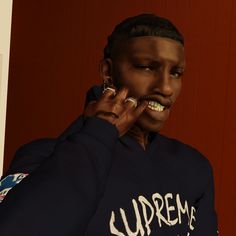 a woman talking on her cell phone while wearing a blue sweatshirt with the supreme logo