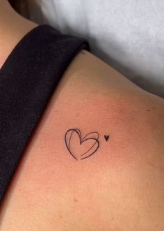 a small heart tattoo on the back of a woman's left arm and shoulder