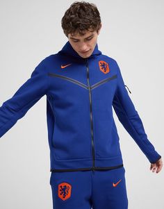 a young man wearing a blue nike jacket and shorts with an orange lion on the side