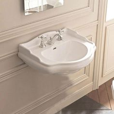 a white sink sitting next to a toilet in a bathroom under a mirror on the wall