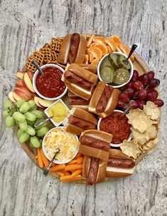 a platter filled with hot dogs, grapes, crackers, and other snacks