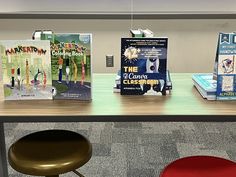 there are several books on the table and one is sitting in front of two stools