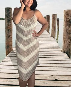 a woman is standing on a dock with her hands in her hair and wearing a knitted dress