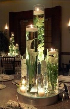 a table topped with lots of vases filled with flowers and candles next to each other