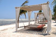 an outdoor bed on the beach with palm trees in the background