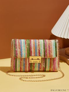 a multicolored handbag sitting on top of a table next to a lamp