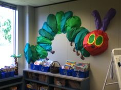 the very hungry caterpillar is hanging on the wall next to bookshelves