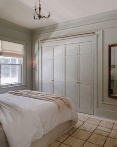 a bedroom with a bed, closets and a chandelier hanging from the ceiling