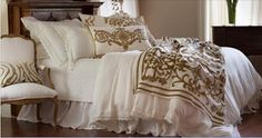 a bed with white and gold comforters on top of it