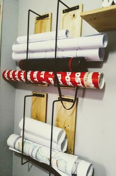 several rolls of paper are hanging on the wall next to some shelves with rolled up papers