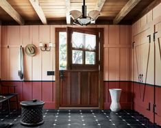 a room with red walls and black flooring has a large wooden door that leads to the outside