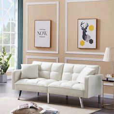 a living room with two pictures on the wall and a white couch in front of it