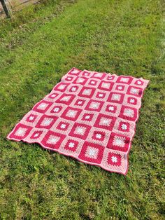 a red and white blanket laying on the grass