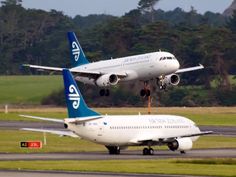 two large air planes are taking off from an airport runway with trees in the background