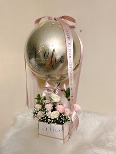 a silver ball with pink flowers and a ribbon around it