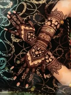 a woman's hands with hennap on her arm and hand covered in intricate designs