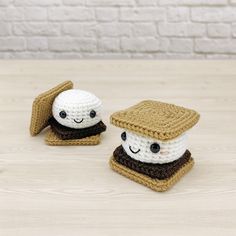 two small crocheted food items sitting on top of a wooden table next to each other