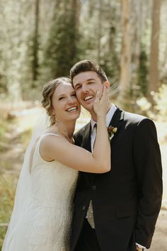 a bride and groom posing for a photo in the woods with their hands on each other's cheek