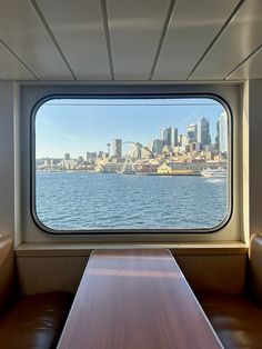 a table and benches in front of a large window overlooking the water with cityscape