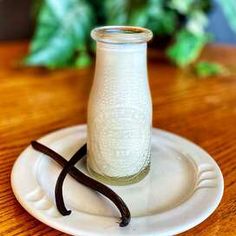 a glass bottle sitting on top of a white plate next to a pair of glasses