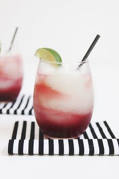 two glasses filled with drinks sitting on top of black and white napkins