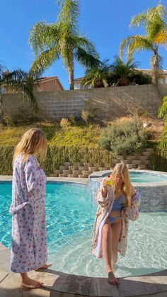 two women in robes standing near a pool