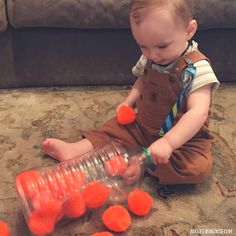 a toddler playing with plastic orange balls on the floor in front of a couch