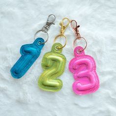 three keychains with the letters g and z on them sitting on a white surface