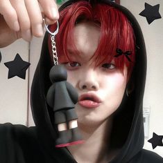 a woman with red hair wearing a black hoodie and holding onto a keychain