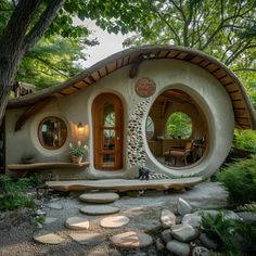 a house made out of rocks in the middle of a forest with trees around it