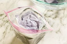 two clear bags filled with something on top of a white marble countertop next to a glass bowl