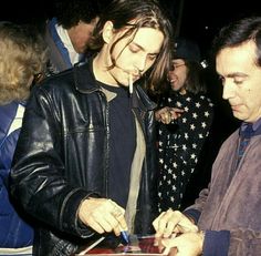 two men standing next to each other while looking at something on a clipboard in front of them