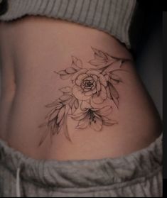 a woman's stomach with a flower tattoo on her lower side ribcage