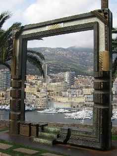 a large mirror sitting on top of a wooden bench next to a body of water