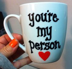 a person holding a coffee cup with the words you're my person on it