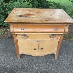 an old wooden dresser sitting in front of some bushes