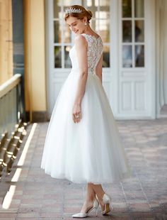 a woman in a white dress is standing on the sidewalk wearing a tiara and heels