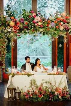 a man and woman sitting at a table with flowers