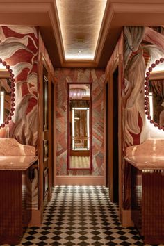 a hallway with two sinks and mirrors on the wall next to each other in front of a checkered floor