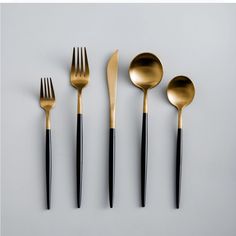 black and gold utensils are lined up on a white surface