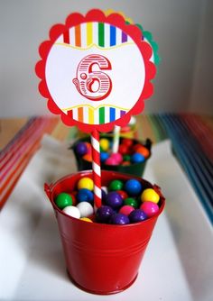 a red bucket filled with candy next to a sign that says'6th birthday '