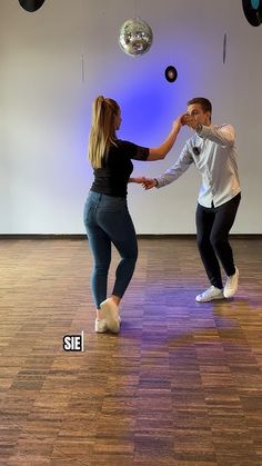 a man and woman dance in an empty room with disco balls hanging from the ceiling