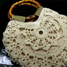 a white crocheted purse sitting on top of a wooden table next to a bamboo handle