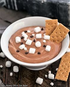 a white bowl filled with chocolate pudding and marshmallows on top of a wooden table